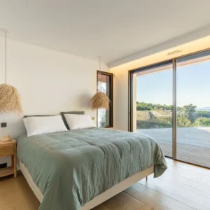 Chambre avec un grand lit double vue mer et accès direct à la terrasse.