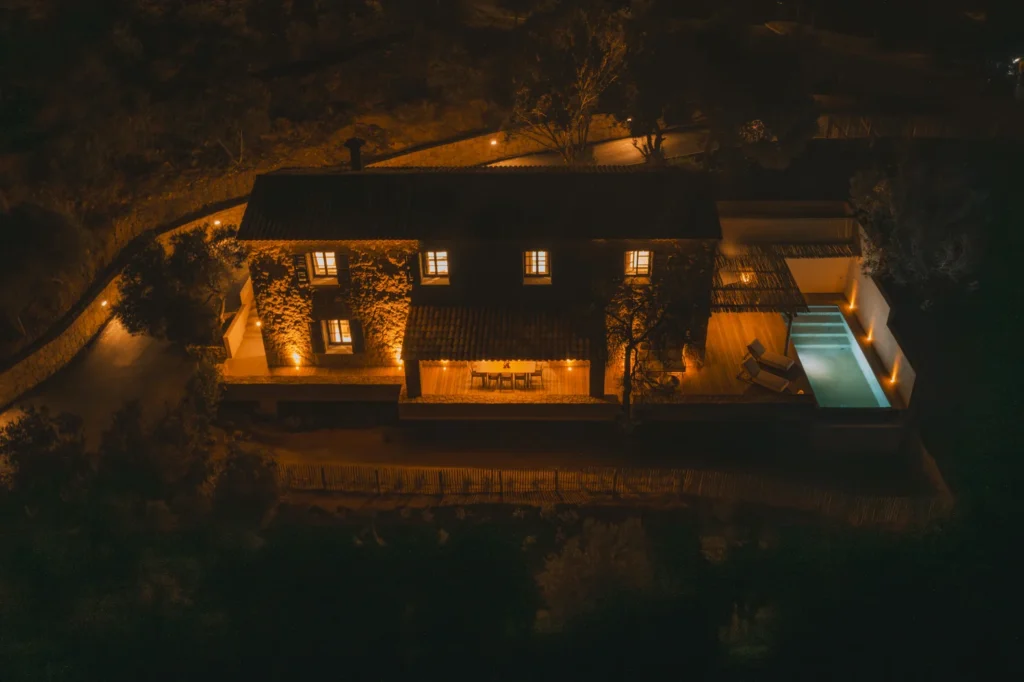 Vue aérienne de nuit de la villa et sa piscine éclairée.