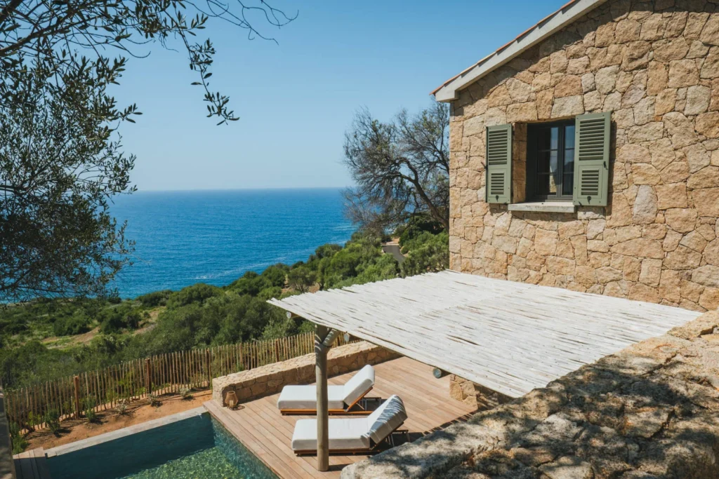 Vue sur la façade de la maison revêtît de pierre ancienne corse et sa piscine.