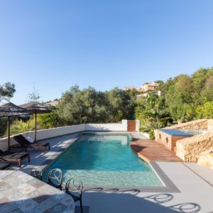 Grande terrasse extérieure avec transat et parasol, piscine et son jacuzzi privé chauffé.