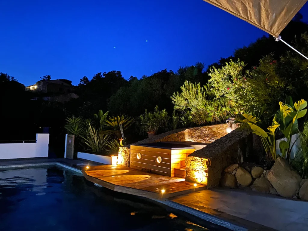 Jacuzzi éclairé de nuit au bord de la piscine.