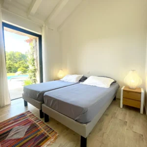 Chambre avec 2 grands lits doubles et accès terrasse extérieure sur la piscine.