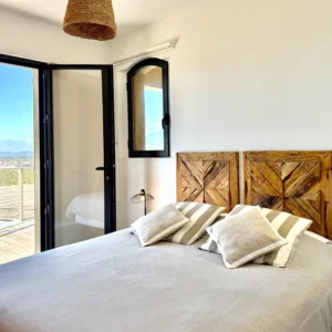 Chambre lumineuse avec lit king size blanc et vue mer