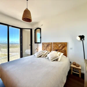 Chambre avec lit king size blanc et vue mer.