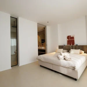 Grande chambre blanche et son lit king size avec salle de bain.