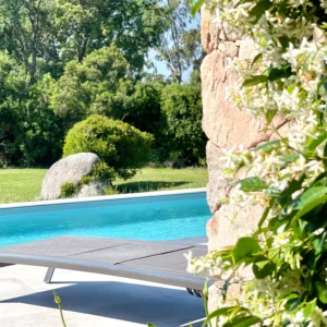 Piscine avec façade de la maison en pierre.