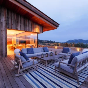 Espace détente extérieur de nuit avec table et canapé, chaise.