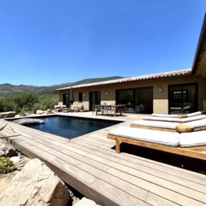 Terrasse avec transat et parasol au bord de la piscine.