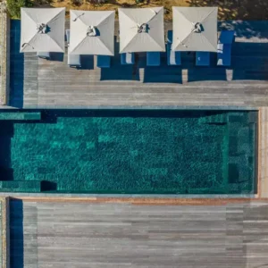 Vue aérienne de la piscine chauffée et sa grande terrasse en bois, équipée de transats et parasols.