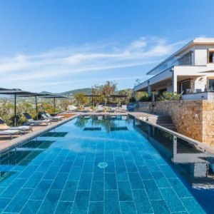 Vue sur toute la piscine et sa grande terrasse équipé de transat et parasol.